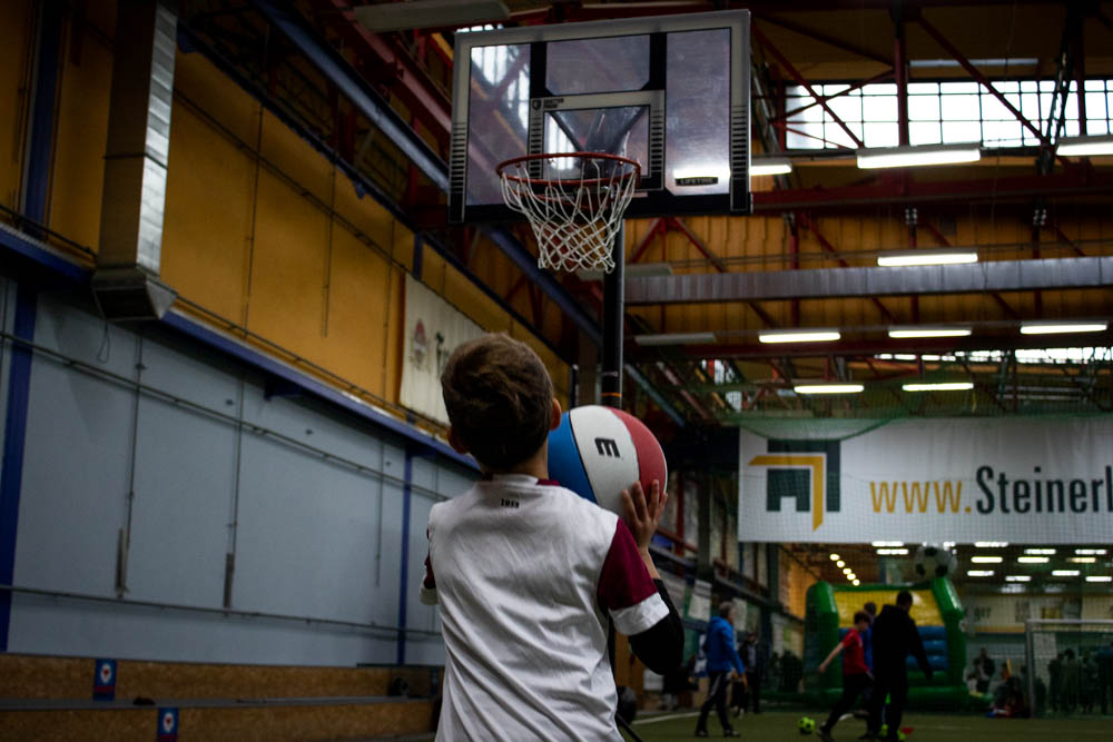 Junge steht mit Ball vor Basketballkorb